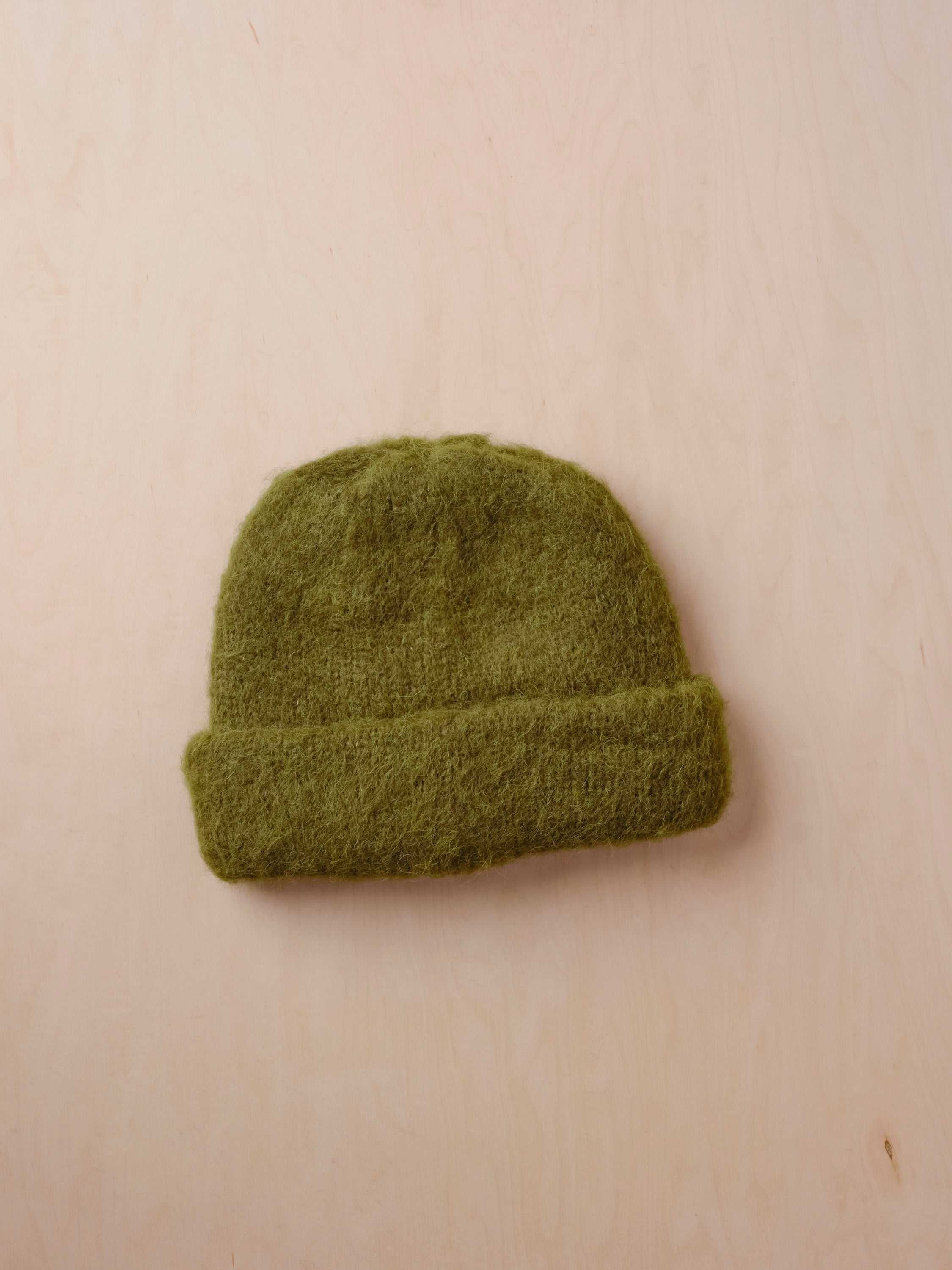 Green knit beanie on a beige background