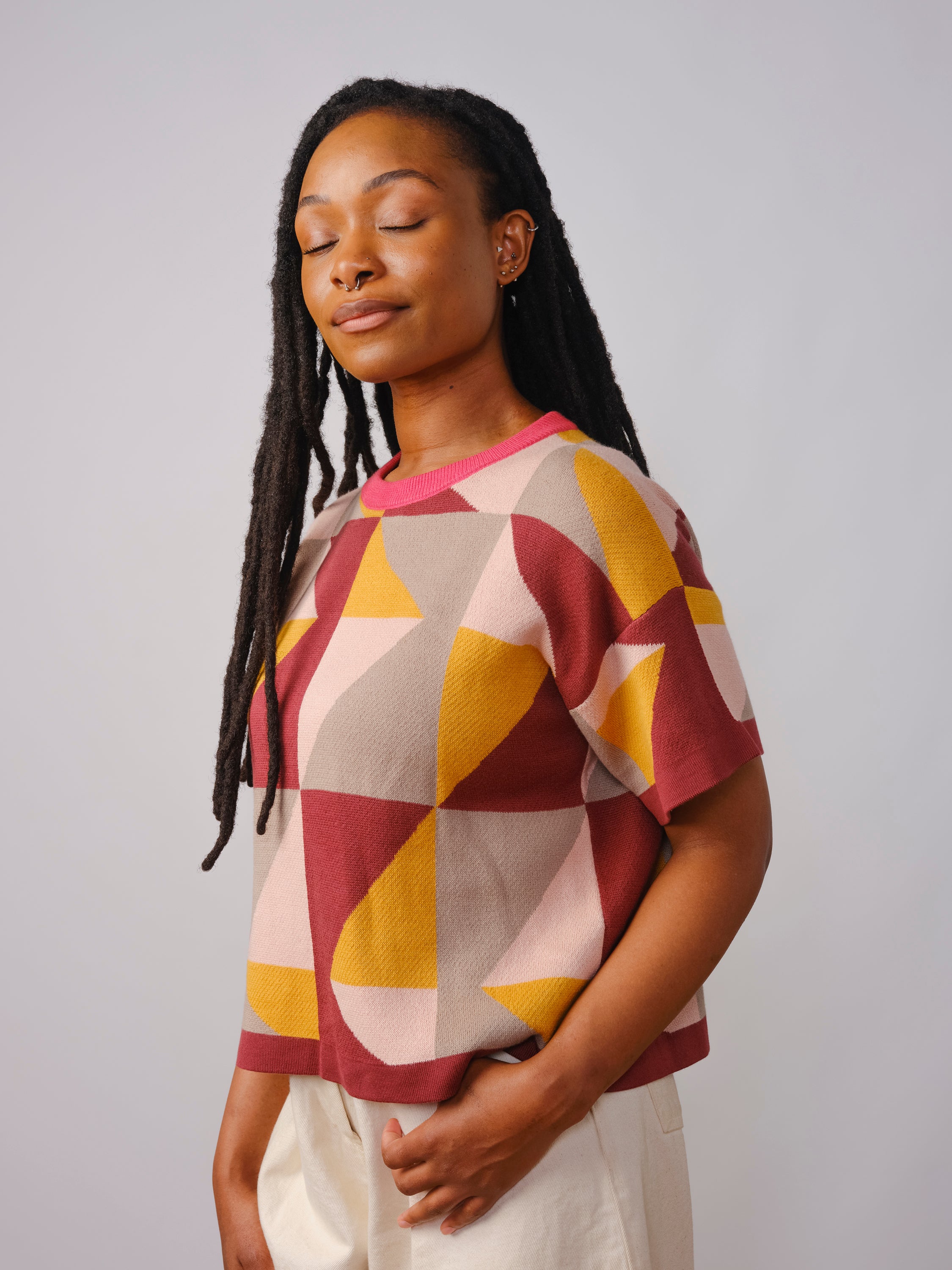 Woman wearing a geometric patterned knit sweater against a plain background